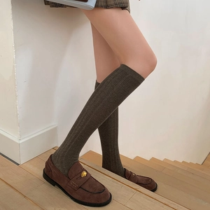 Detail of dark brown ribbed knit knee-high socks paired with vintage loafers on stairs