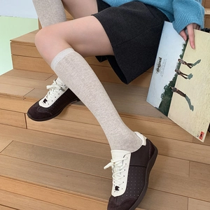 Close-up of beige ribbed knit calf socks paired with vintage brown and cream sneakers