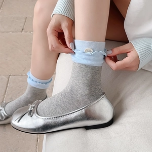 Blue and grey ruffled knit socks with decorative buttons and ballet flats on a soft background