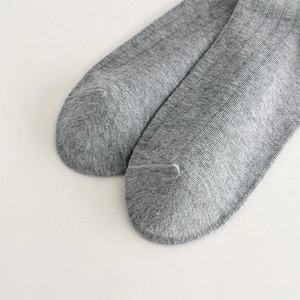 Détail de chaussettes hautes grises à côtes montrant la couture lisse et la texture