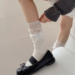Detail of white lace trim socks with silk bow paired with Mary Jane leather shoes