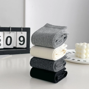 Gros plan de quatre paires de chaussettes hautes côtelées en gris, beige, gris et noir