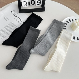 Gros plan détaillé de chaussettes en maille côtelée noire, grise et crème sur table