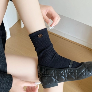 Detail of ribbed crew socks with golden bow buckles paired with quilted Mary Jane shoes