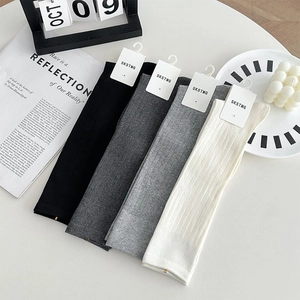 Détail de quatre paires de chaussettes montantes en maille côtelée noire, grise et blanc cassé