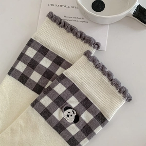 Detailed knit texture of checkered socks with cute cartoon dog embroidery and wavy cuffs