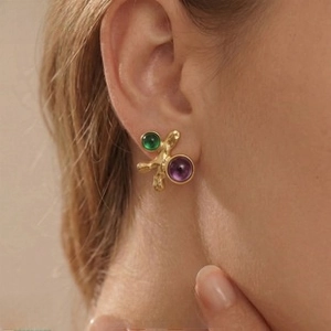 Detail of vintage irregular gold stud earrings with green and purple gemstones on model