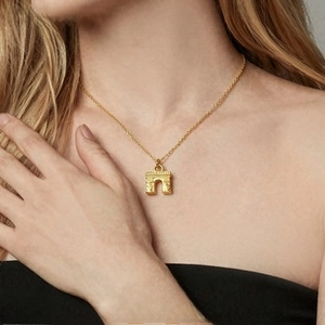 Detail of gold Arch de Triumph pendant necklace on model with refined texture