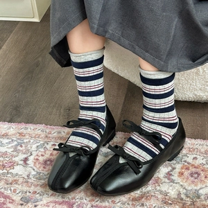 Dettaglio di calzini in cotone a righe con scarpe Mary Jane nere su tappeto retrò