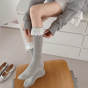 Close-up of sweet grey knit knee-high socks with delicate white floral lace trim details