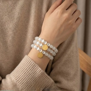 Detailed macro of a triple-layered cat eye pearl bracelet with gold Fu pendant