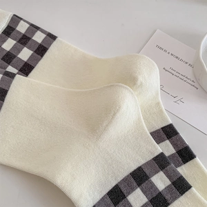 Close-up of cream knit socks with checkerboard pattern and ribbed texture detail