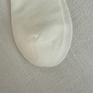 Close-up of white knit socks showing fine vertical texture and premium toe stitching detail