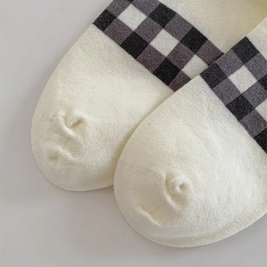 Close-up of cream gingham pattern socks with fine knitted cotton texture on the toe area