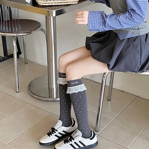 Detail von grauen Overknee-Socken mit weißen Punkten, Spitzenbesatz und Smile-Stickerei