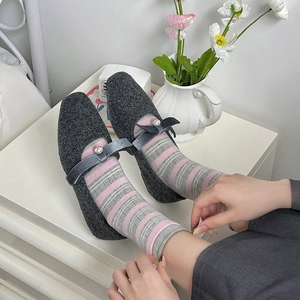 Dettaglio di scarpe Mary Jane grigie con perle e fiocco abbinate a calze a righe