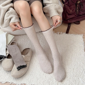 Chaussettes côtelées beige avec bordure ondulée contrastée sur tapis en fausse fourrure