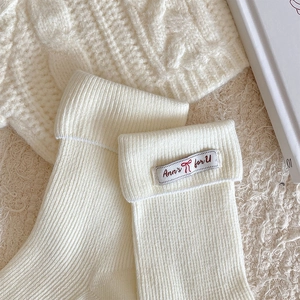 Detail of white ribbed cotton socks with folded cuffs and a decorative fabric label