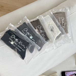 Close-up of five pairs of cotton socks in individual zipper bags on white fabric
