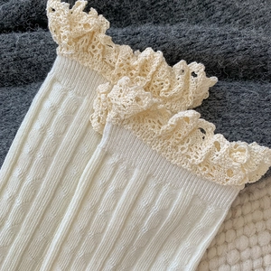 Close-up of cream white ribbed socks with vintage crochet lace trim and knit texture