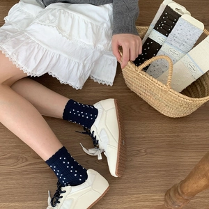 Close-up of knit crew socks with white polka dots and delicate wavy lace trim