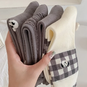 Detailed view of grey and beige knitted winter socks with cute animal embroidery and patterns