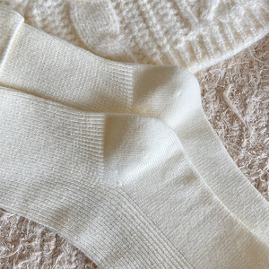 Macro shot of vertical ribbed knit texture on cream-colored cotton mid-calf socks