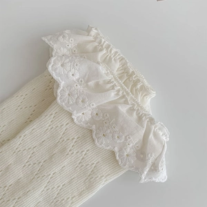 Detail of white cotton knitted socks with layered lace ruffle trim and floral embroidery
