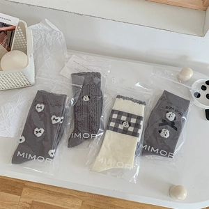 Close-up of four pairs of grey knit socks with puppy embroidery and bow details