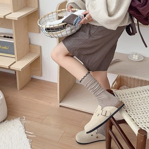 Vue détaillée des mules en daim beige avec boucles métalliques et chaussettes grises en coton
