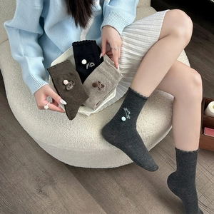 Detailed close-up of cute cat embroidery and pom-poms on knitted crew socks