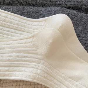 Detail of white waffle knit cotton calf socks with ribbed cuffs and vintage texture