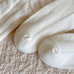 Detailed close-up of white ribbed knit fabric texture on cotton crew socks