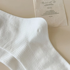 Dettaglio di calze in cotone bianco a coste con tallone rinforzato e trama