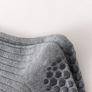 Macro view of grey knit yoga socks featuring anti-slip black silicone dots on the heel