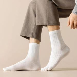 Detail of white cotton five-finger socks with ribbed texture worn with brown pants