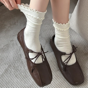 Dettaglio di scarpe Mary Jane marroni con fiocco sottile e calze con volant bianchi