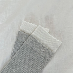 Detail of grey ribbed knit socks featuring a white contrast cuff and soft cotton texture