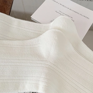 Macro shot of white ribbed knit fabric texture on solid color mid-calf cotton socks