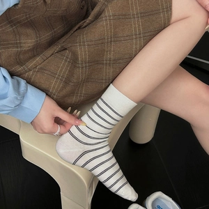 Detailed texture of white crew socks with black horizontal stripes and ribbed cuffs