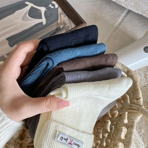 Close-up of ribbed knit socks in five neutral colors with a small fabric logo label