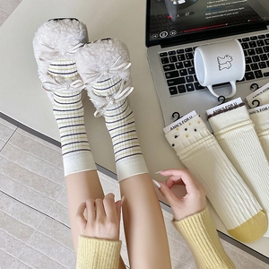 Detailed view of women's fluffy striped socks with bow accents and soft plush texture