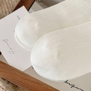Macro shot of white ribbed cotton mid-calf socks showing fine texture and clean toe seam