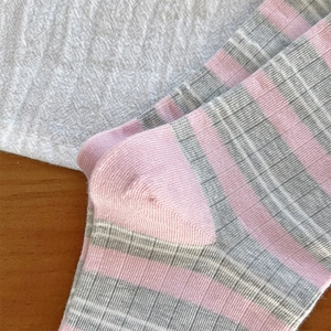 Dettaglio ravvicinato di calze a righe rosa e grigie con cuciture rifinite sul tallone