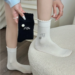 Close-up of cute cat embroidery and 3D pom-pom detail on ruffled crew socks for women