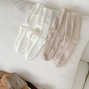 Detailed close-up of ribbed texture on white and beige mid-calf knitted cotton socks