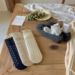 Detailed view of polka dot cotton socks in navy, cream, and white on wooden background