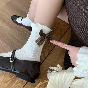 Detail von cremefarbenen Vintage-Socken mit gestreifter Schleife und Rüschenrand