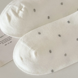 Detailed macro view of white cotton crew socks featuring grey polka dots and flat toe seams