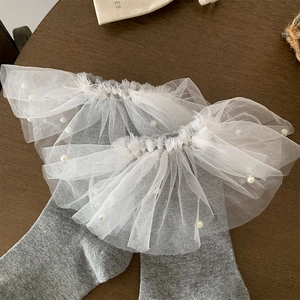 Détail de chaussettes grises avec dentelle en tulle blanc et ornements de perles nacrées
